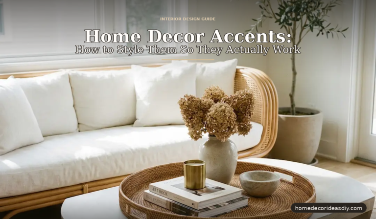 A beautifully styled living room scene showing home decor accents arranged on a rattan tray — featuring a ceramic vase with dried flowers, a brass candle holder, stacked books, and a small stone bowl on a white coffee table, with a rattan sofa and olive tree in the backgroun