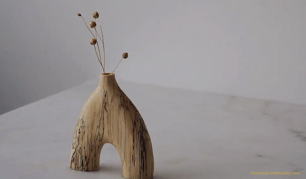 Salted wood arch vase with dried seed pods on a marble surface one of the luxury decorative objects that work without flowers