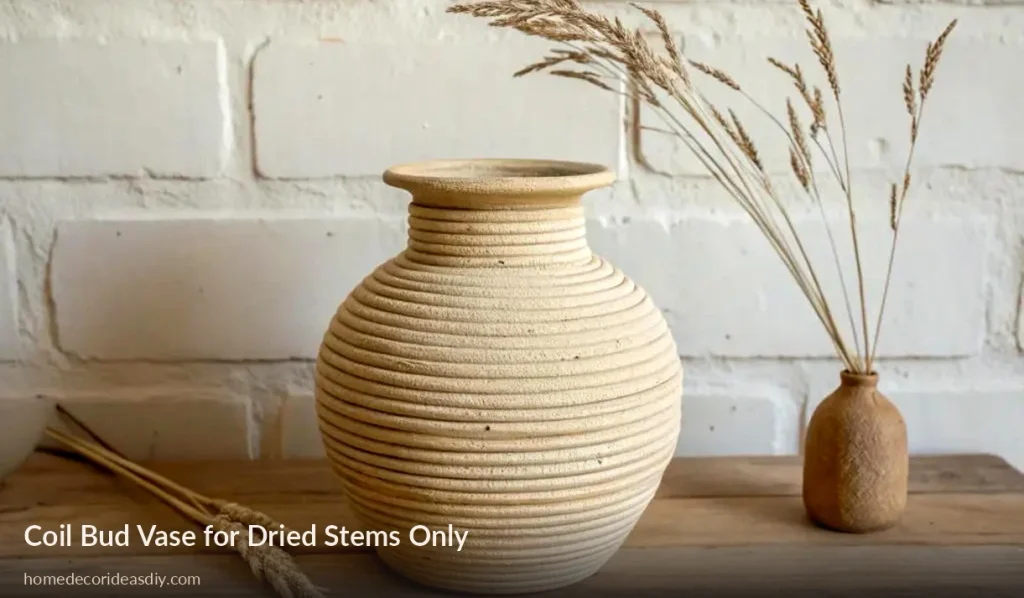 Coil-built clay vase with dried grass on a wooden tabl