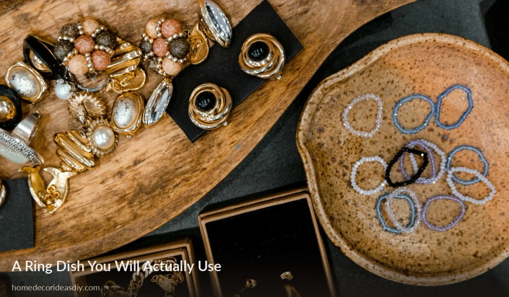 Speckled clay ring dish holding beaded rings next to a wooden jewelry tray diy clay home decor