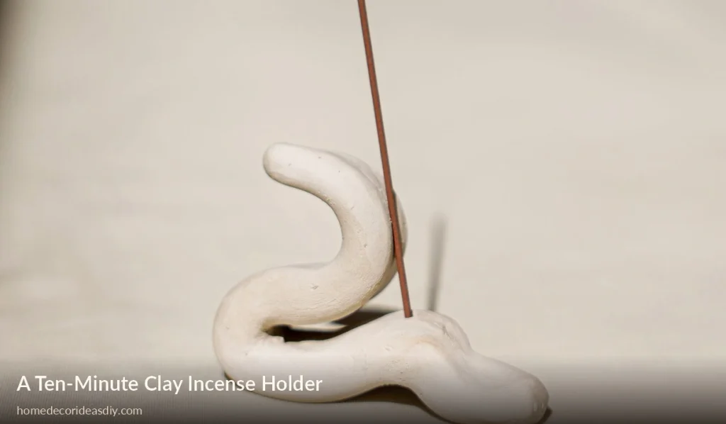 Simple handmade clay incense holder with a burning stick