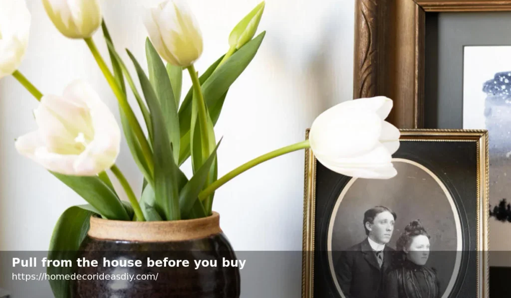 White tulips in a thrifted pot beside an old frame
