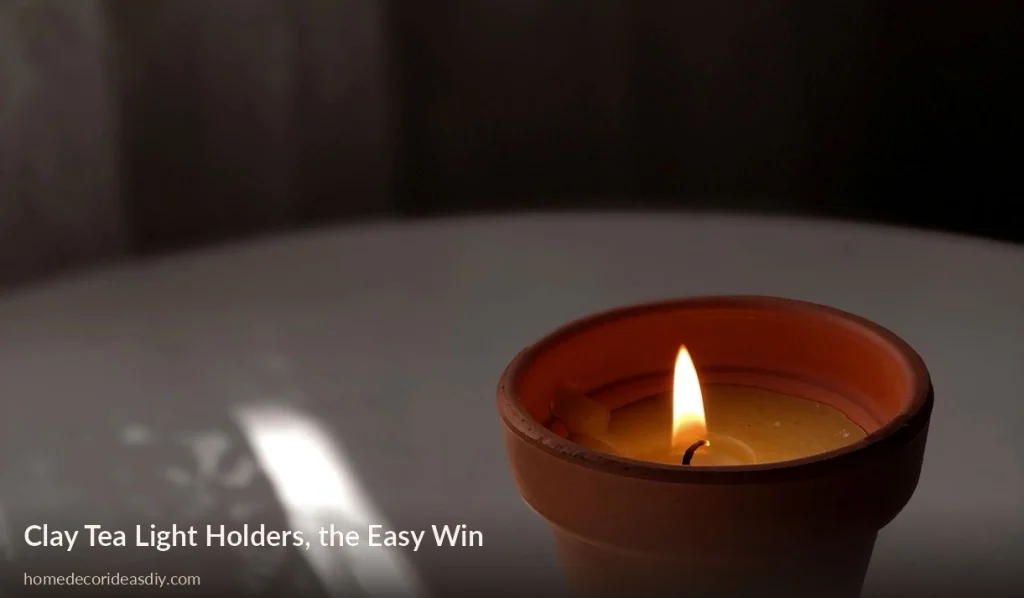 Lit candle in a small terracotta clay holder on a table