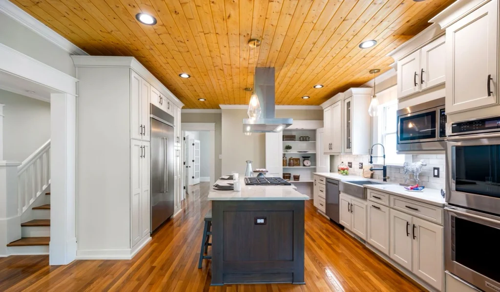 Kitchen island with a clear walkway on both sides, painted cabinets and pendant lights above