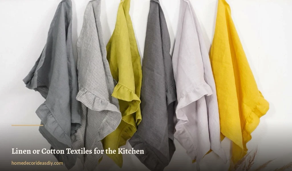 Row of linen kitchen towels in grey, chartreuse, lilac and yellow hanging against a white wall