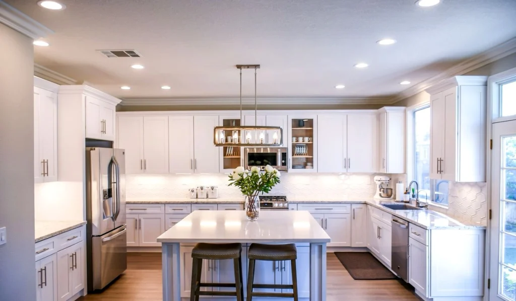 White modern kitchen cabinets with under-cabinet lighting and two stools at a central island