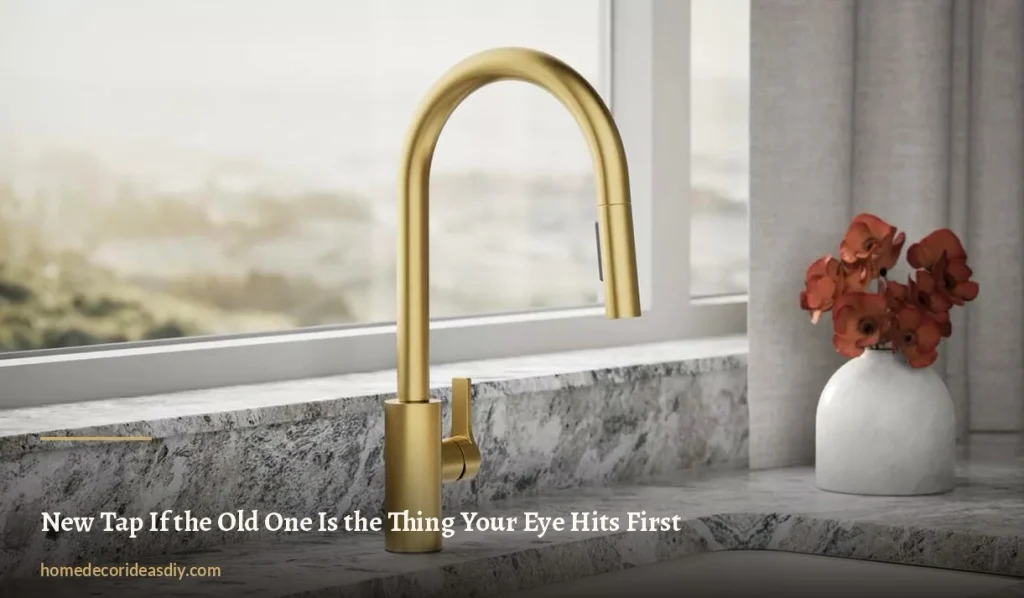 Brushed brass pull-down kitchen tap on a granite worktop beside a white vase of red flowers