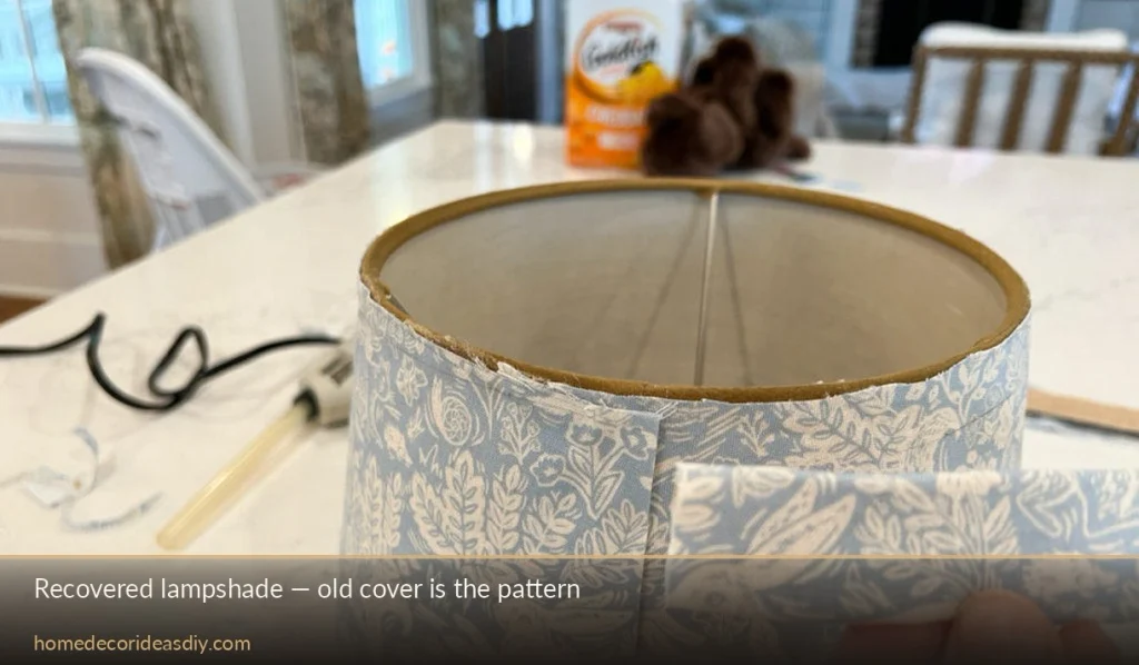 Old lampshade being wrapped with printed cotton using the peeled cover as a pattern