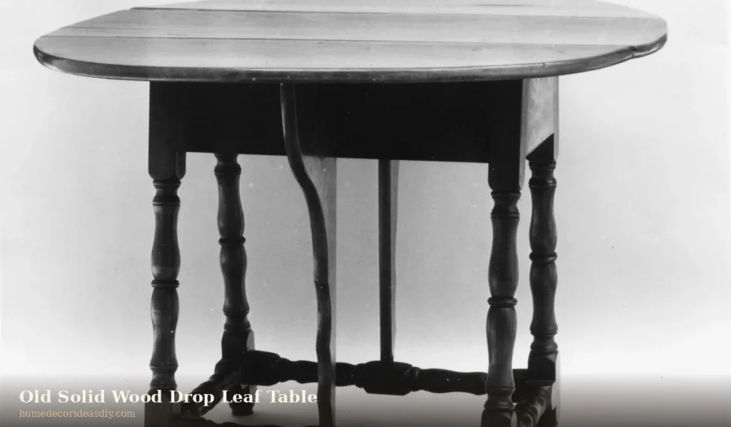 Old solid wood drop leaf table with turned legs.